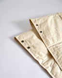 Up-close of buttons on beige down feather shawl by Iwata on a gray background