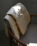 beige down feather shawl by Iwata draped on a chair