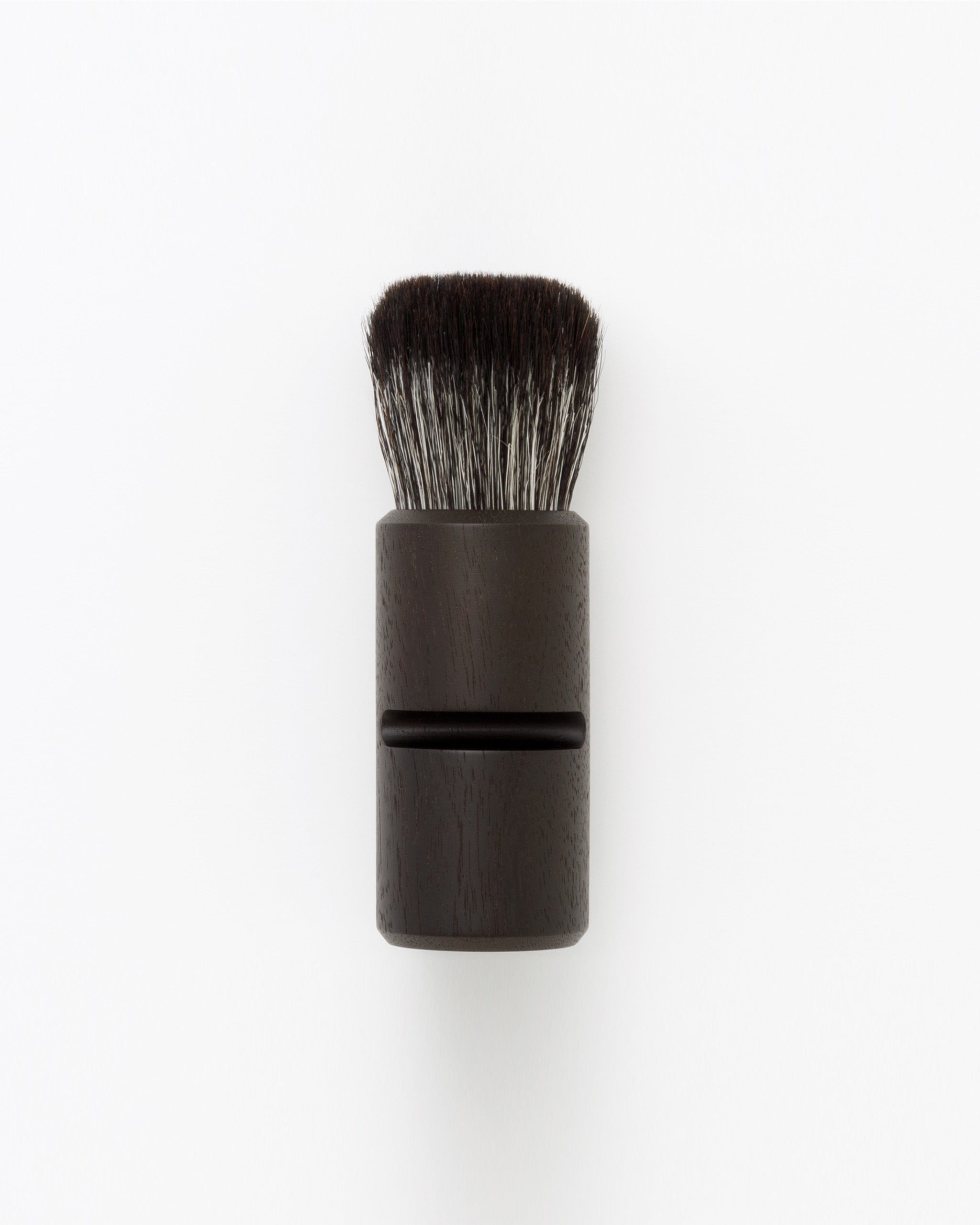 Silhouetted image of hard Jiva face cleansing and shaving series walnut, boar bristle, and goat hair brush by Shaquda against white-gray background.