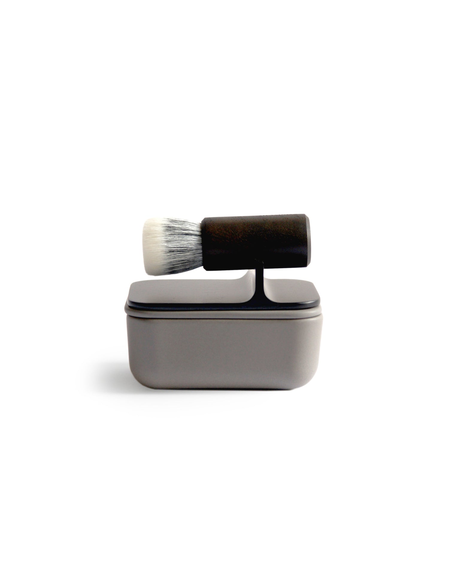 Silhouetted image of soft Jiva face cleansing and shaving series with porcelain bowl and walnut, boar bristle, and goat hair brush by Shaquda against white background.