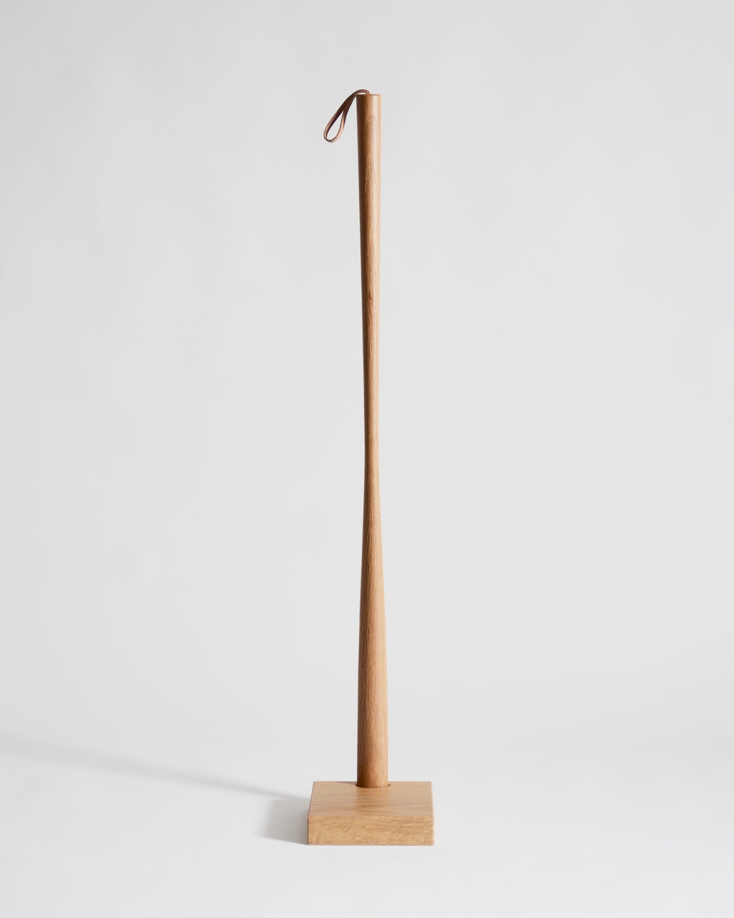 Wooden shoe horn with square base by Nalata Nalata and Kime on a gray background