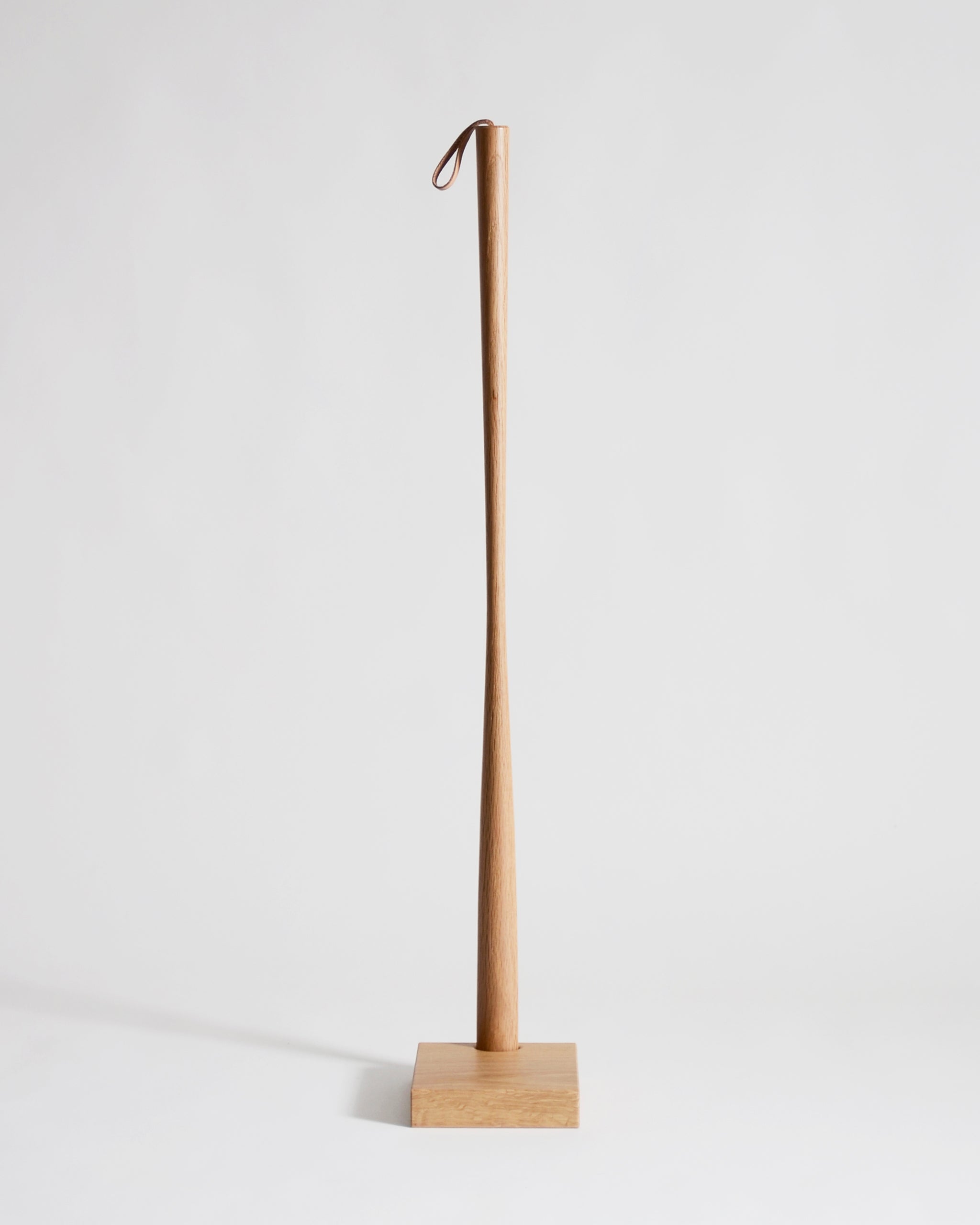 Wooden shoe horn with square base by Nalata Nalata and Kime on a gray background