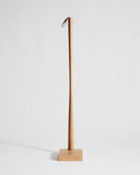 Wooden shoe horn with square base by Nalata Nalata and Kime on a gray background