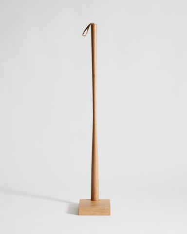 Wooden shoe horn with square base by Nalata Nalata and Kime on a gray background