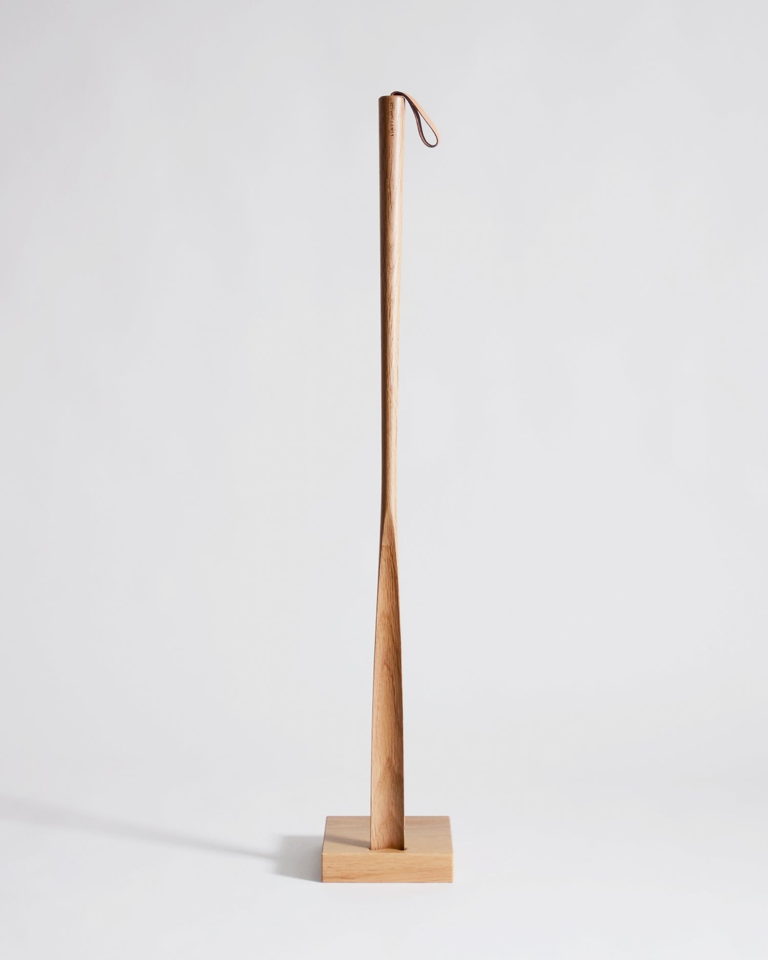 Wooden shoe horn with square base by Nalata Nalata and Kime on a gray background