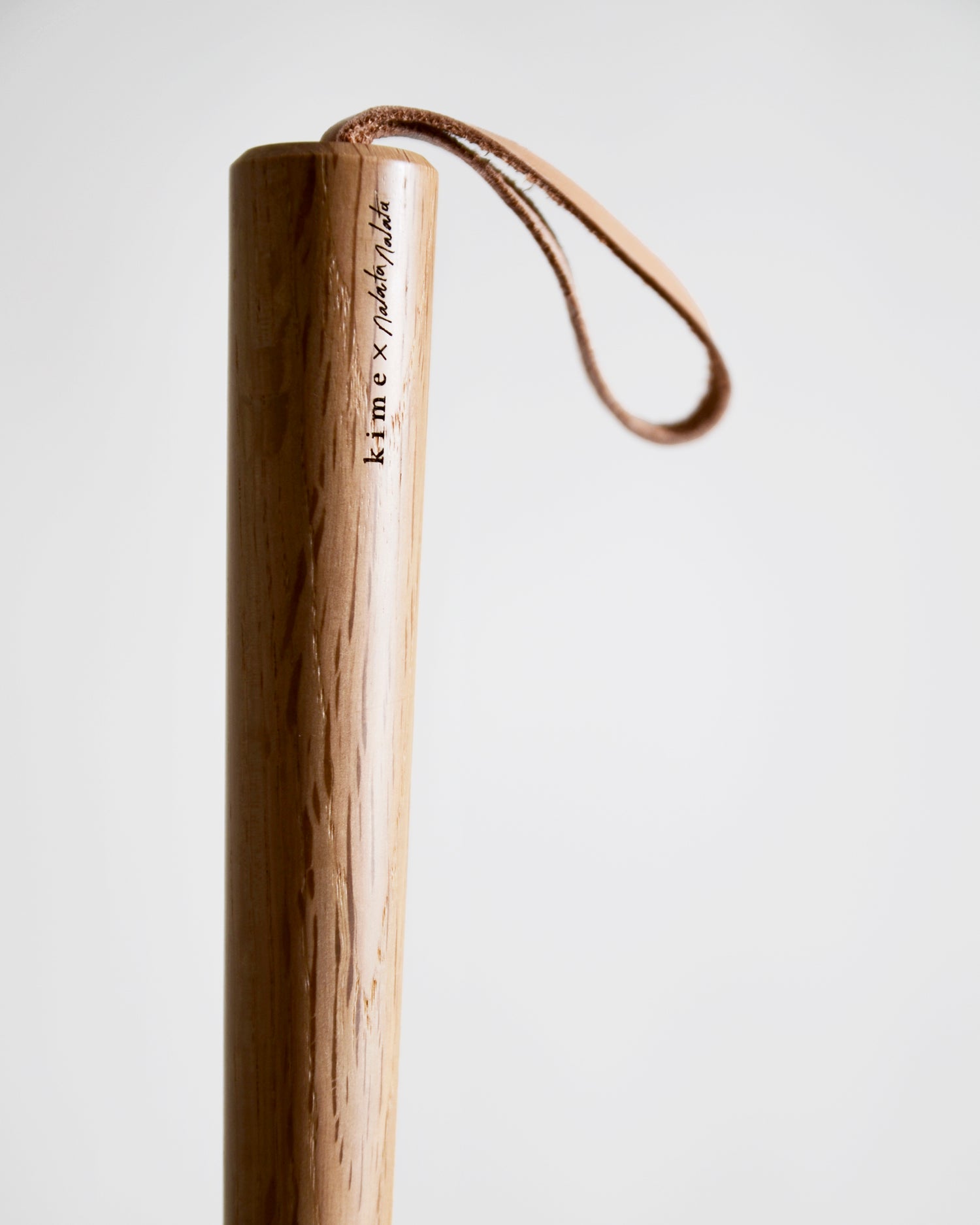 Up-close of wooden shoe horn handle by Nalata Nalata and Kime on a gray background