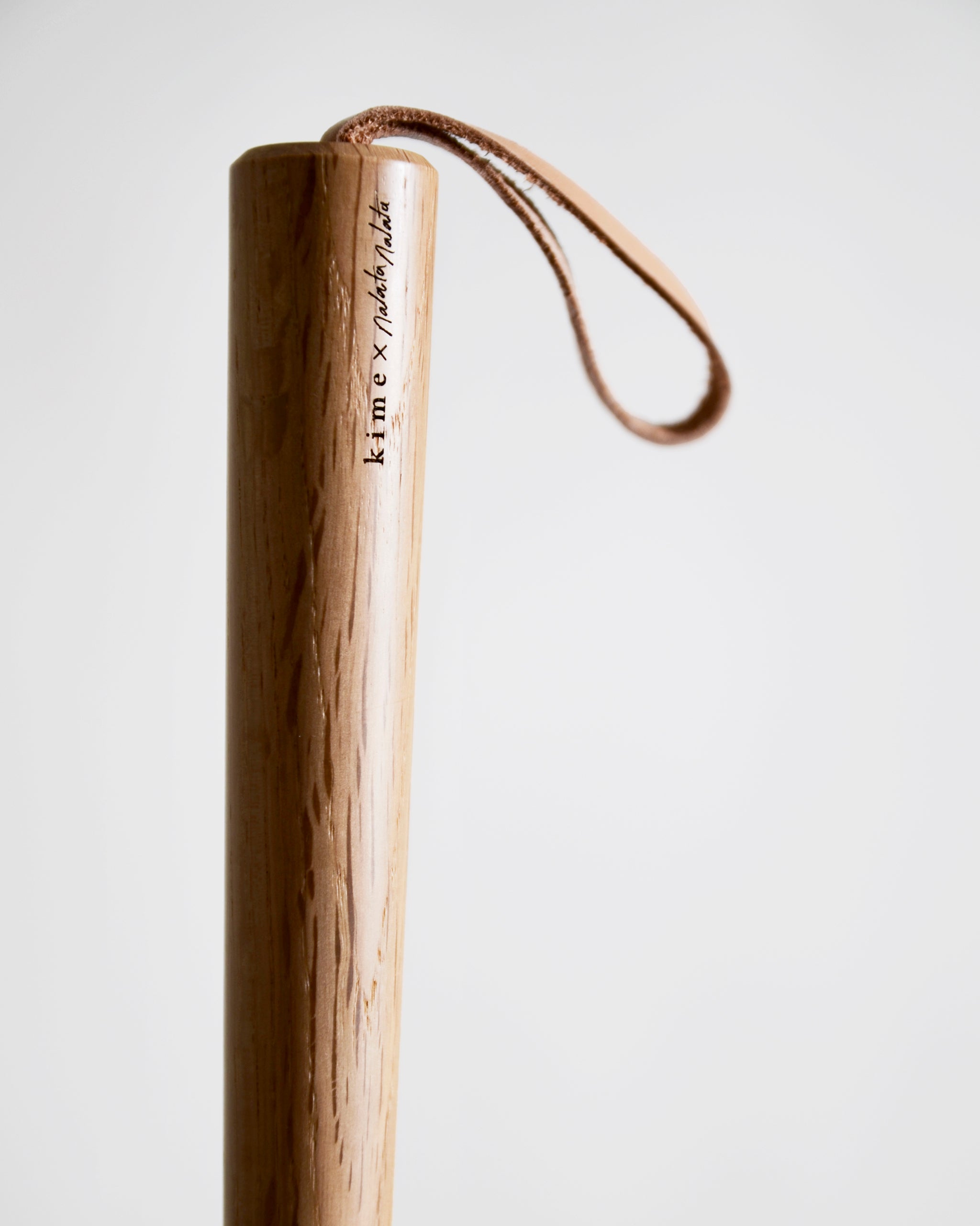Up-close of wooden shoe horn handle by Nalata Nalata and Kime on a gray background