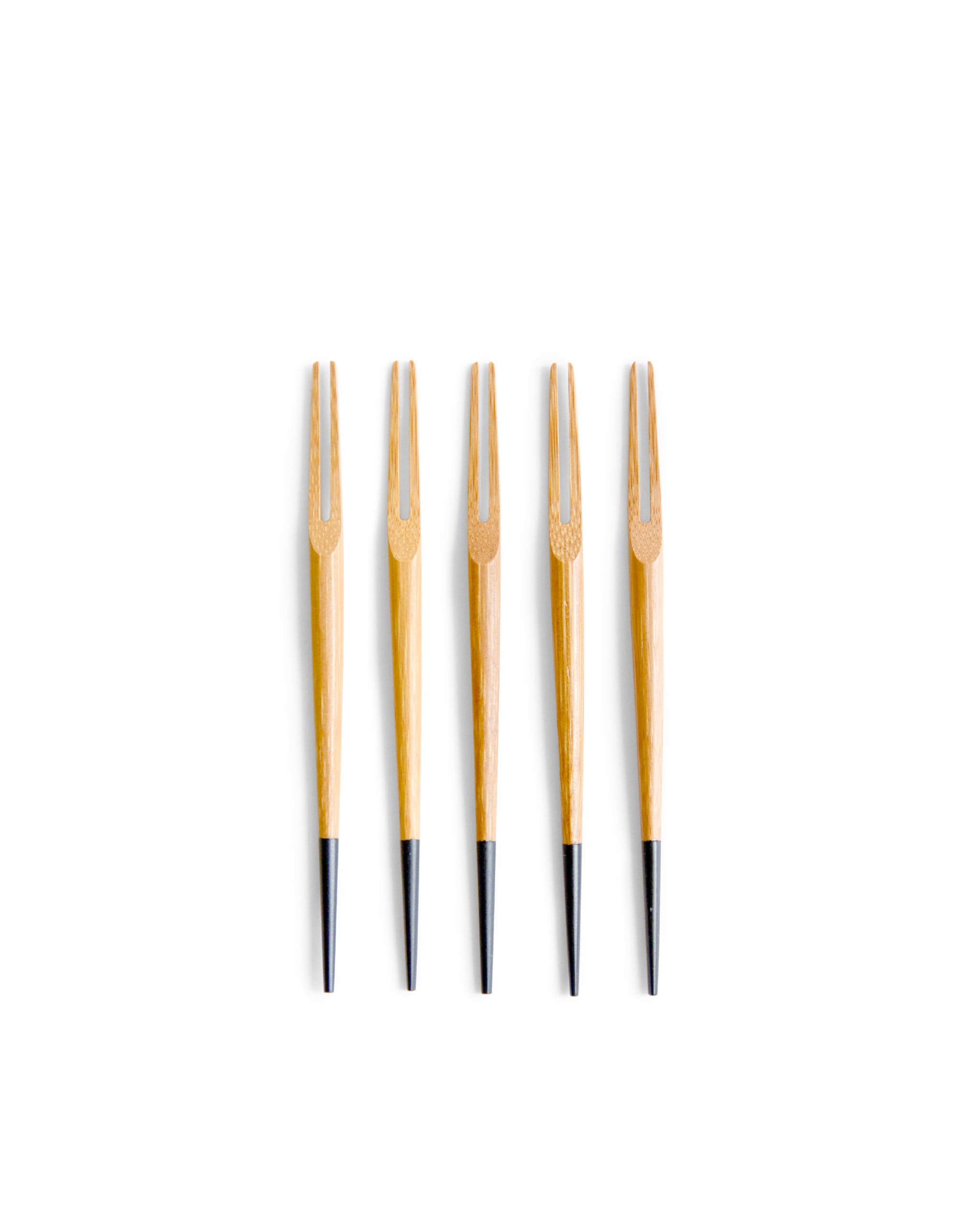 Five small two pronged bamboo forks by Kohchosai Kosuga with black ends in a row against a white background