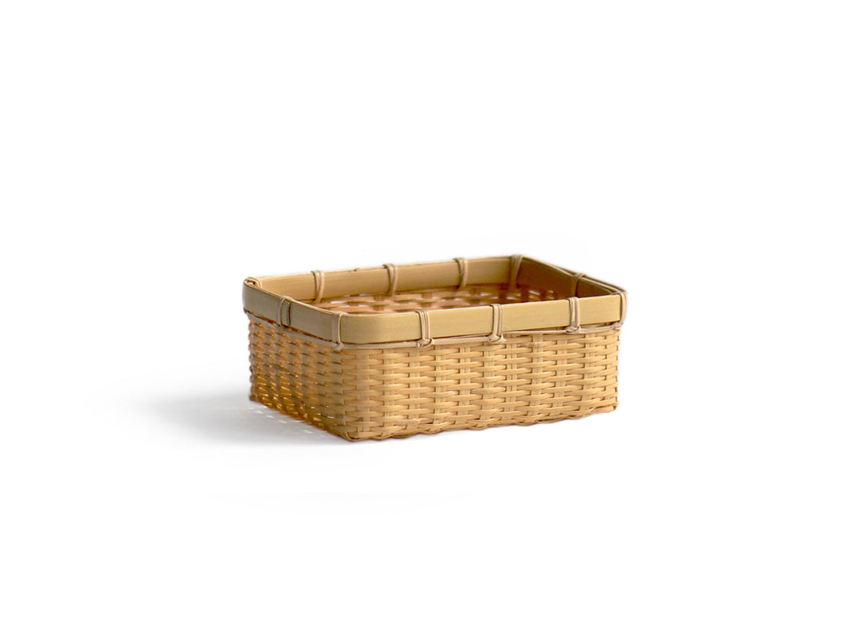 Silhouetted image of small woven rectangular basket by Kochosai Kosuga against white background. 