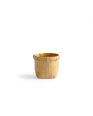 Silhouetted image of small round woven basket by Kohchosai Kosuga against white background. 