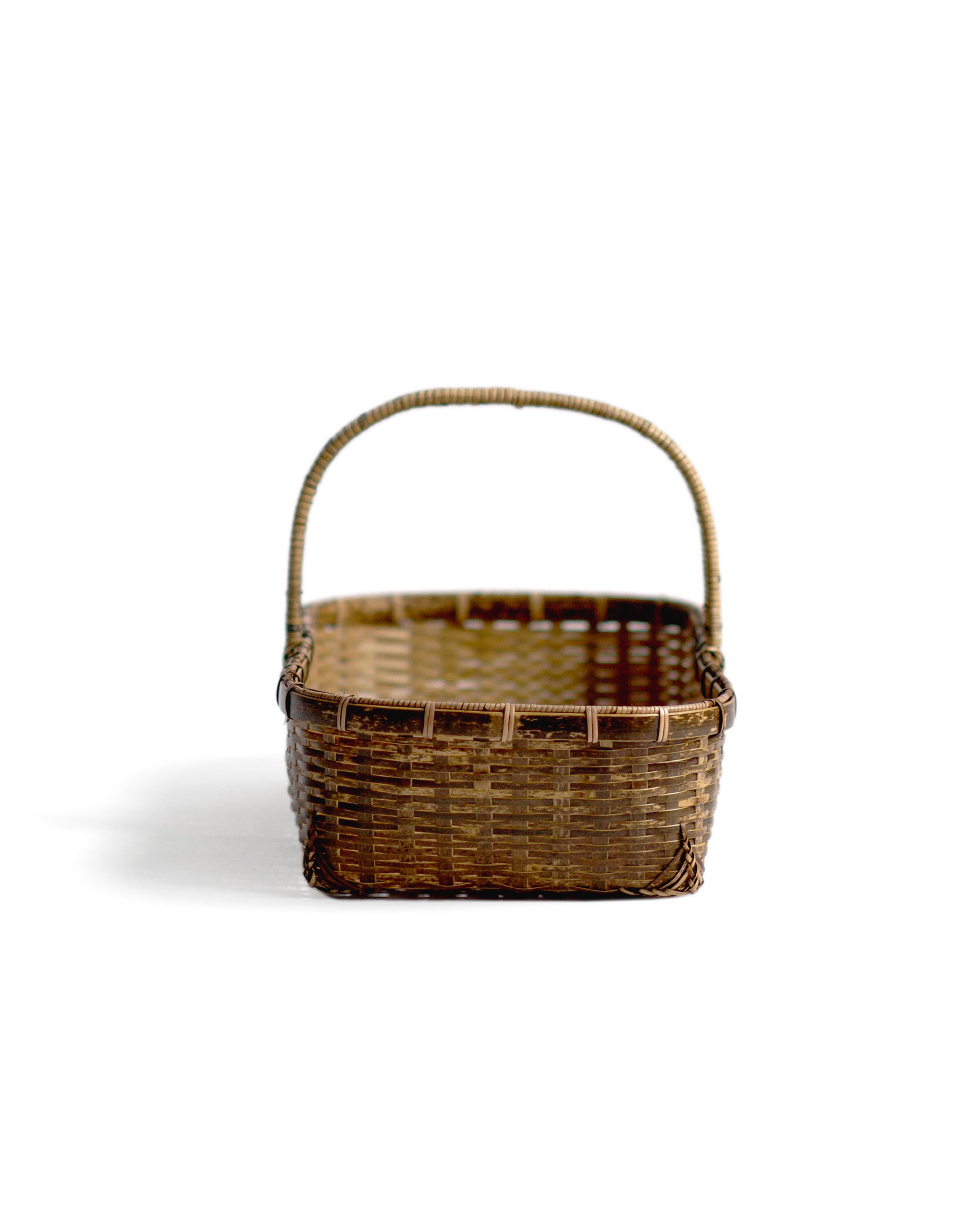 Silhouetted front image of long toradake bread basket with handle by Kohchosai Kosuga against white background.