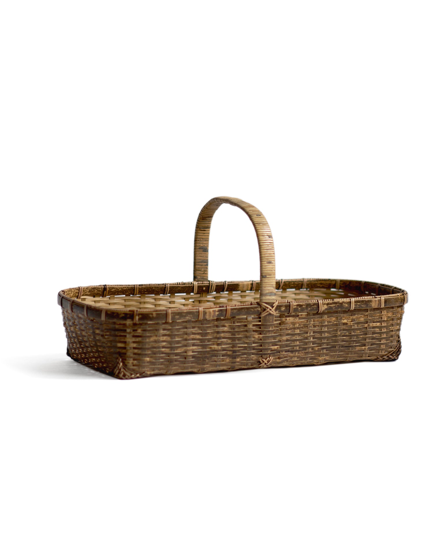 Silhouetted angled image of long toradake bread basket with handle by Kohchosai Kosuga against white background.