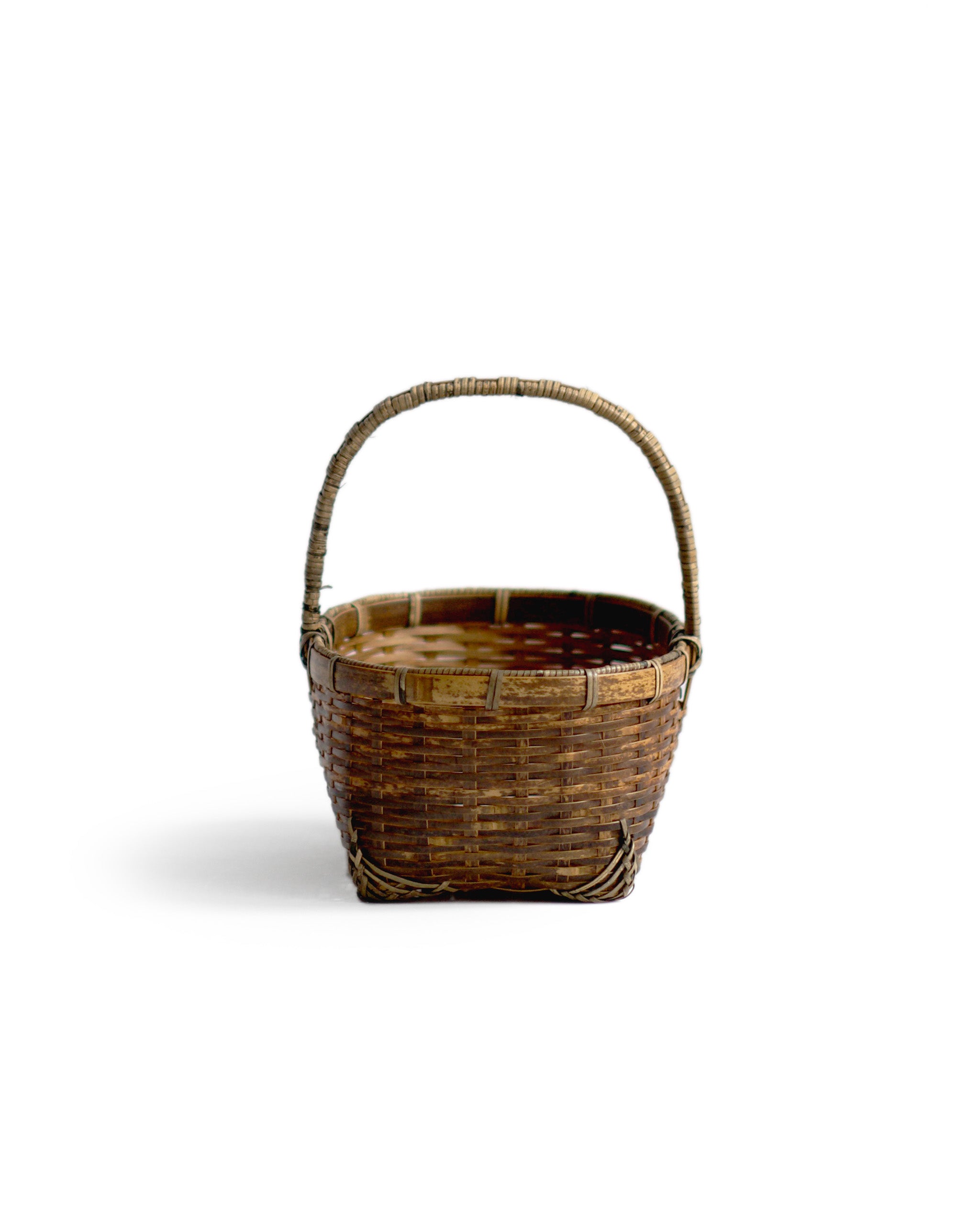 Silhouetted front image of small toradake bread basket with handle by Kohchosai Kosuga against white background.
