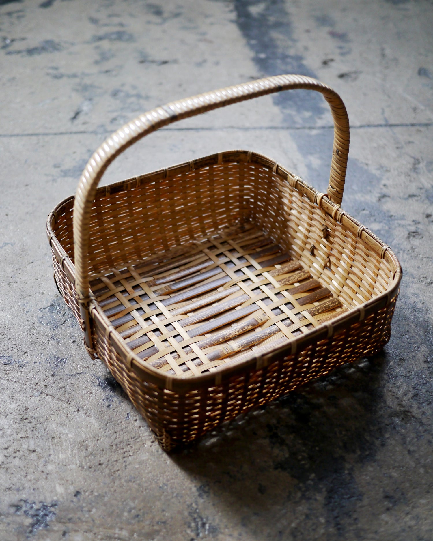 Bird's-eye-view of square toradake bread basket with handle by Kohchosai Kosuga on dark concrete floor.