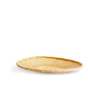 Round low plate-like tray made out of natural colored woven bamboo. It sits against white background.