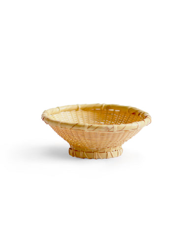 Small bowl made out of natural colored woven bamboo sitting against a white background.