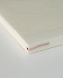 Cropped image focusing on the spine with bookmark string of midori blank a5 notebook.