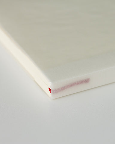 Cropped image focusing on the spine with bookmark string of midori blank a5 notebook.