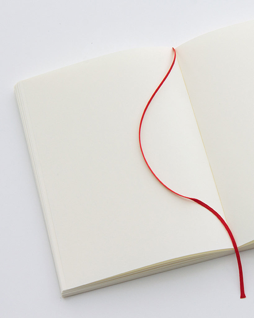 Cropped image focusing on the bookmark string across the open midori blank a5 notebook.