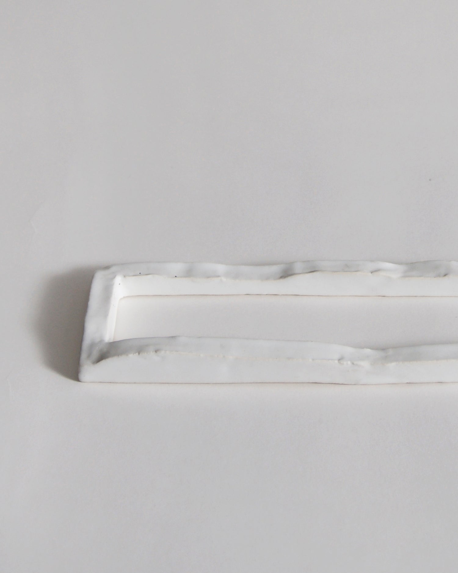 Up-close of white ceramic boundary sculpture by Masanobu Ando on a gray background