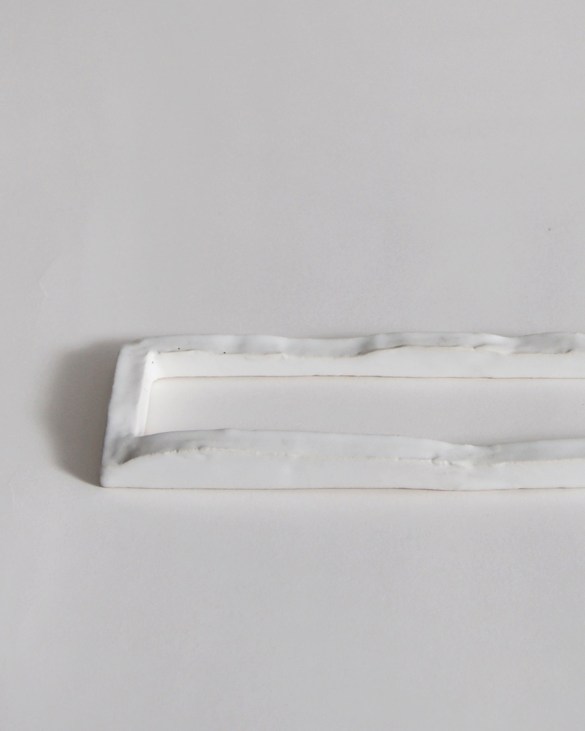 Up-close of white ceramic boundary sculpture by Masanobu Ando on a gray background