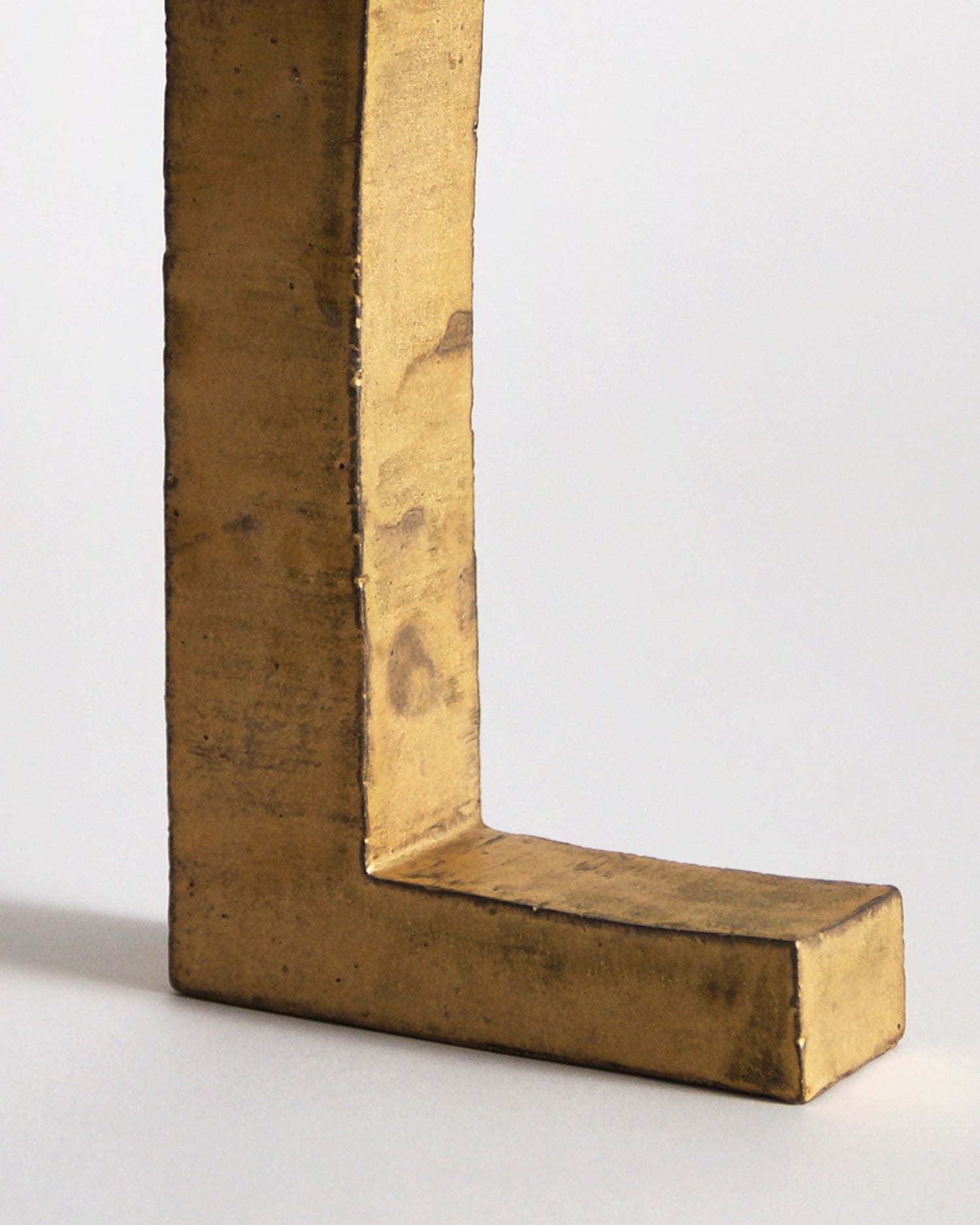 Upclose of bottom of Gold Hanging Vase by Masanobu Ando on a gray background