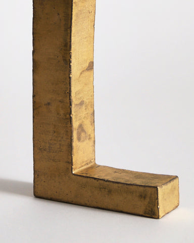 Upclose of bottom of Gold Hanging Vase by Masanobu Ando on a gray background