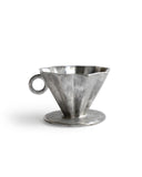 Detail view of the silver glazed coffee dripper silhouetted against white background.