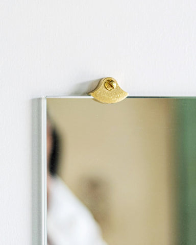 Straight view of one matureware mirror stopper holding a square mirror.