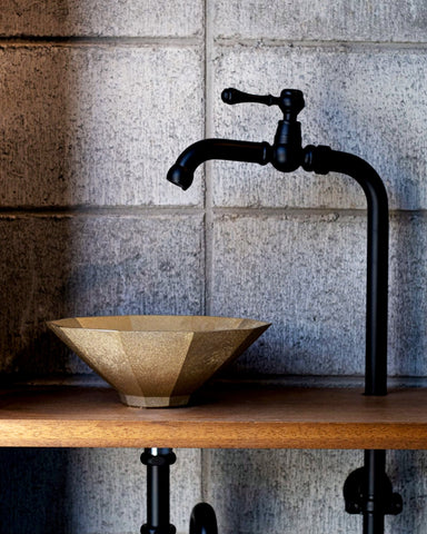 Matureware wash bowl is installed on a wooden countertop, connected to a black pipe and faucet. 