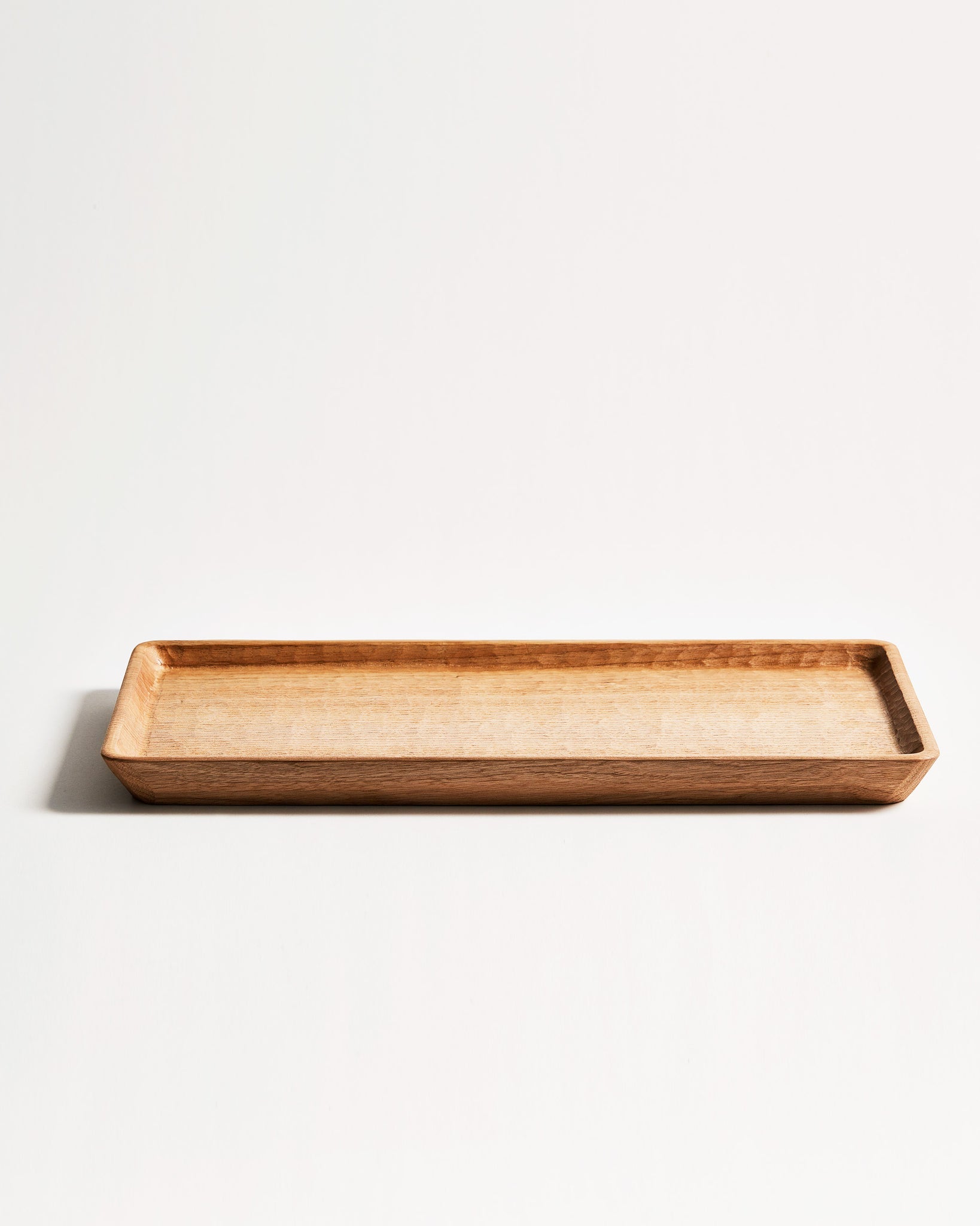 Side view of Japanese Walnut Long Tray with Nano Glass Finish by Ryuji Mitani against white-gray background.