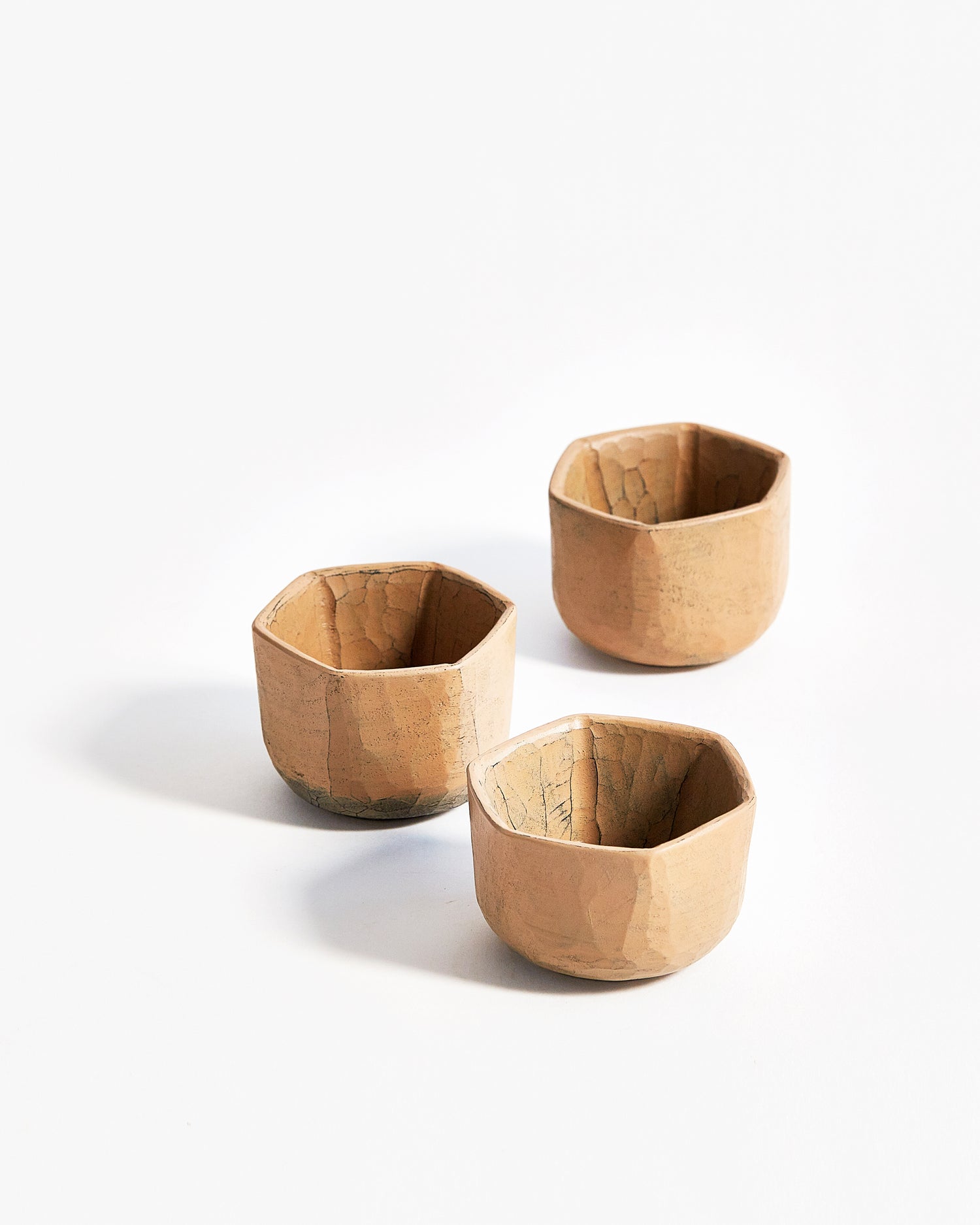 Angled image of arrangement of 3 Hexagonal White Urushi Sake Cups by Ryuji Mitani against white-gray background.