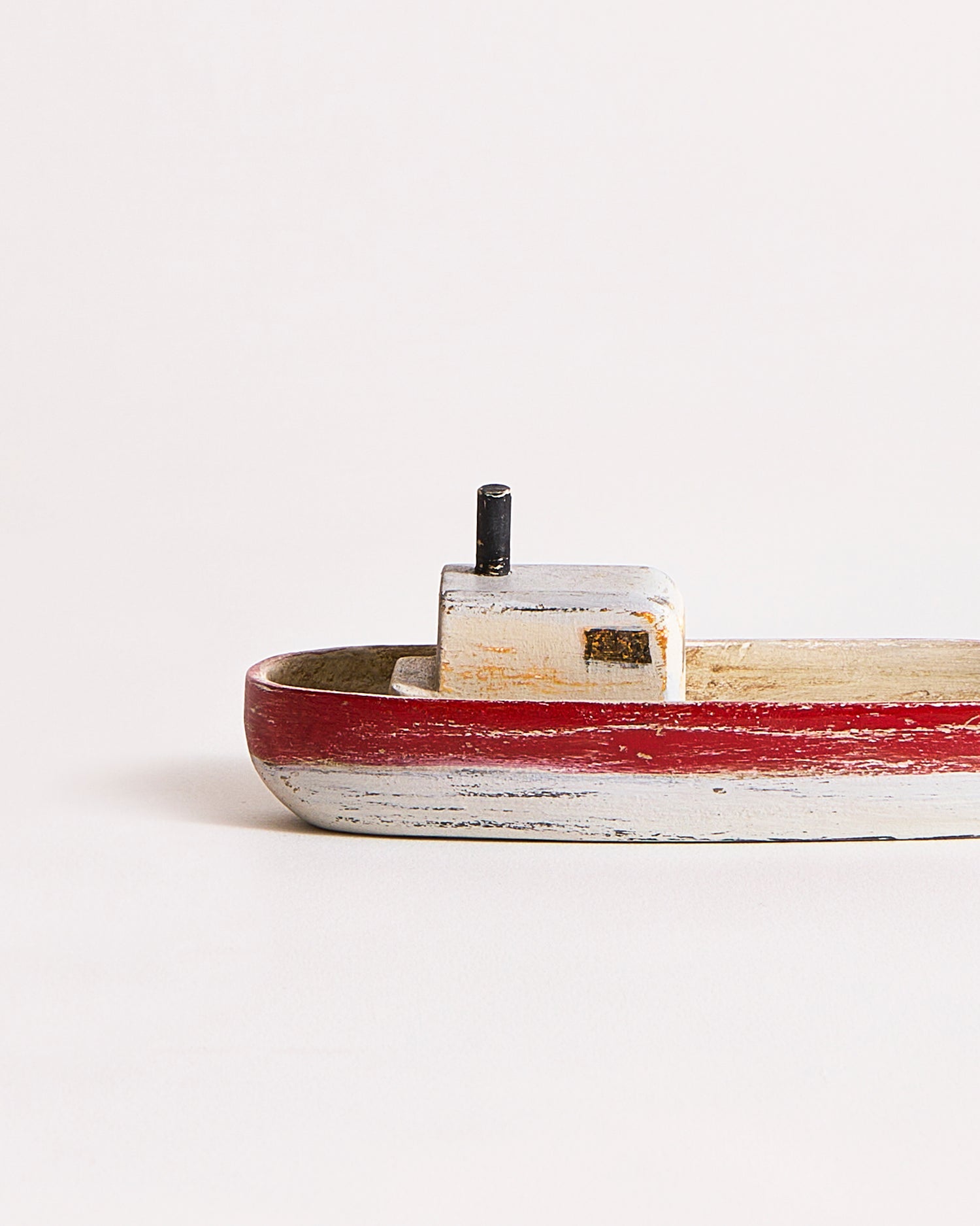 The backside details of a small wooden boat with red, gray, and black paint by Ryuji Mitani on a gray background