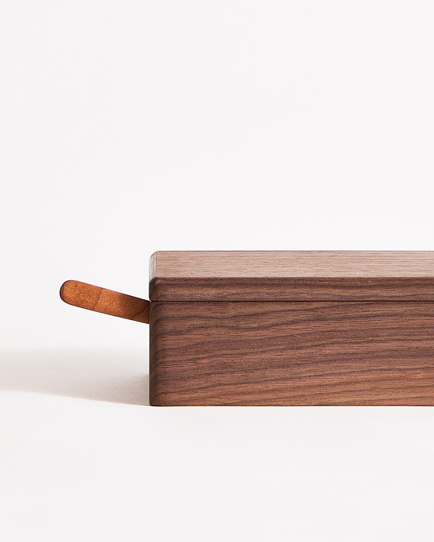 Up-close end of wooden butter box with a wooden knife nestled inside on a gray background