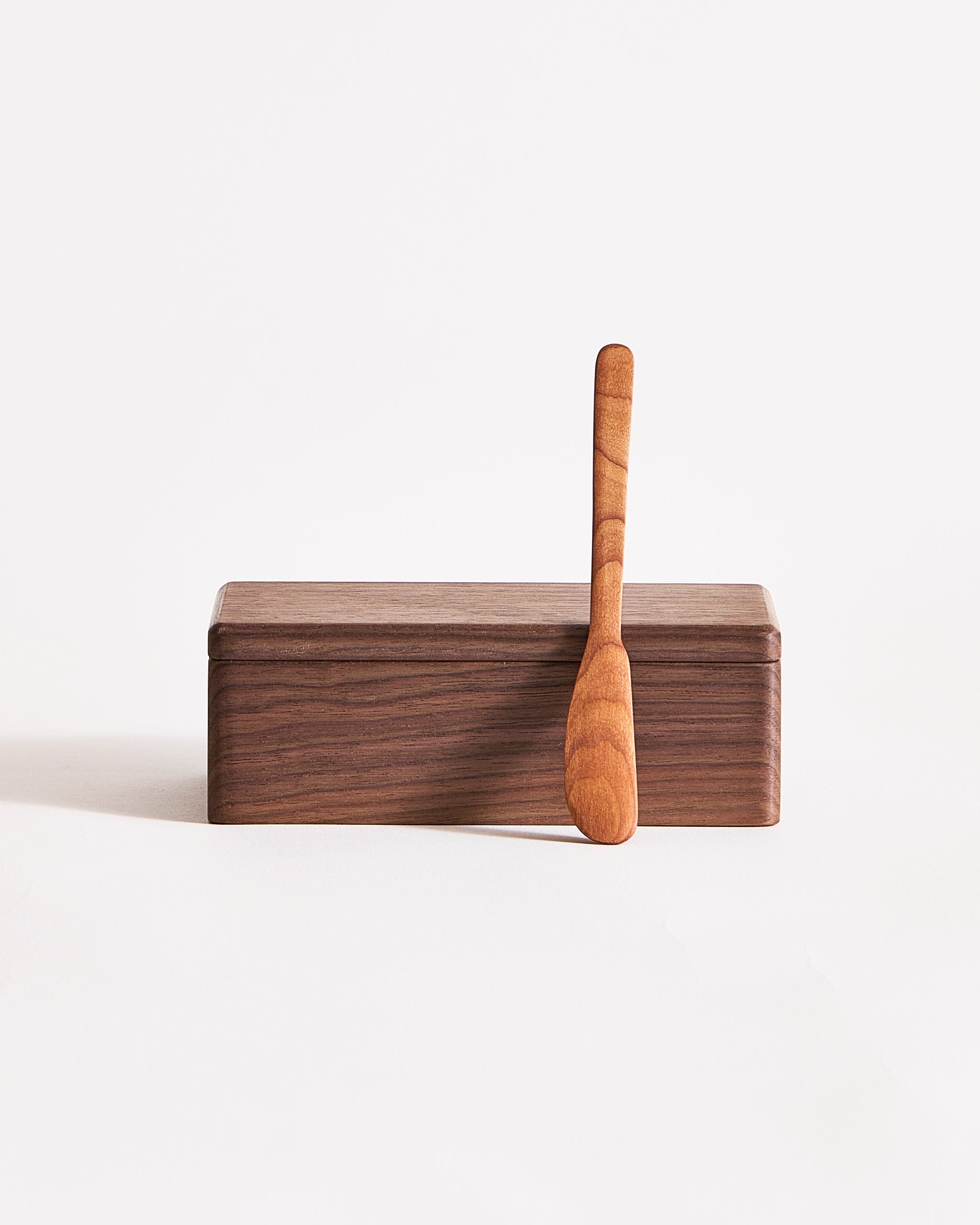 Wooden butter box with a knife  laying on the outside by Ryuji Mitani on a gray background