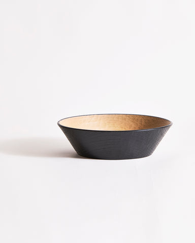 Wooden bowl by Ryuji Mitani with beige interior and black exterior on a gray background