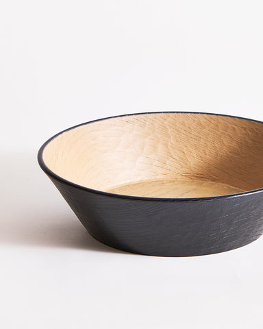 Up-close left corner of a wooden bowl with beige interior and black exterior by Ryuji Mitani on a gray background