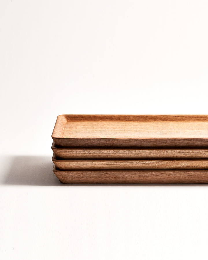 Cropped front view of 4 stacked Japanese Walnut Long Trays with Nano Glass Finish by Ryuji Mitani against white-gray background.