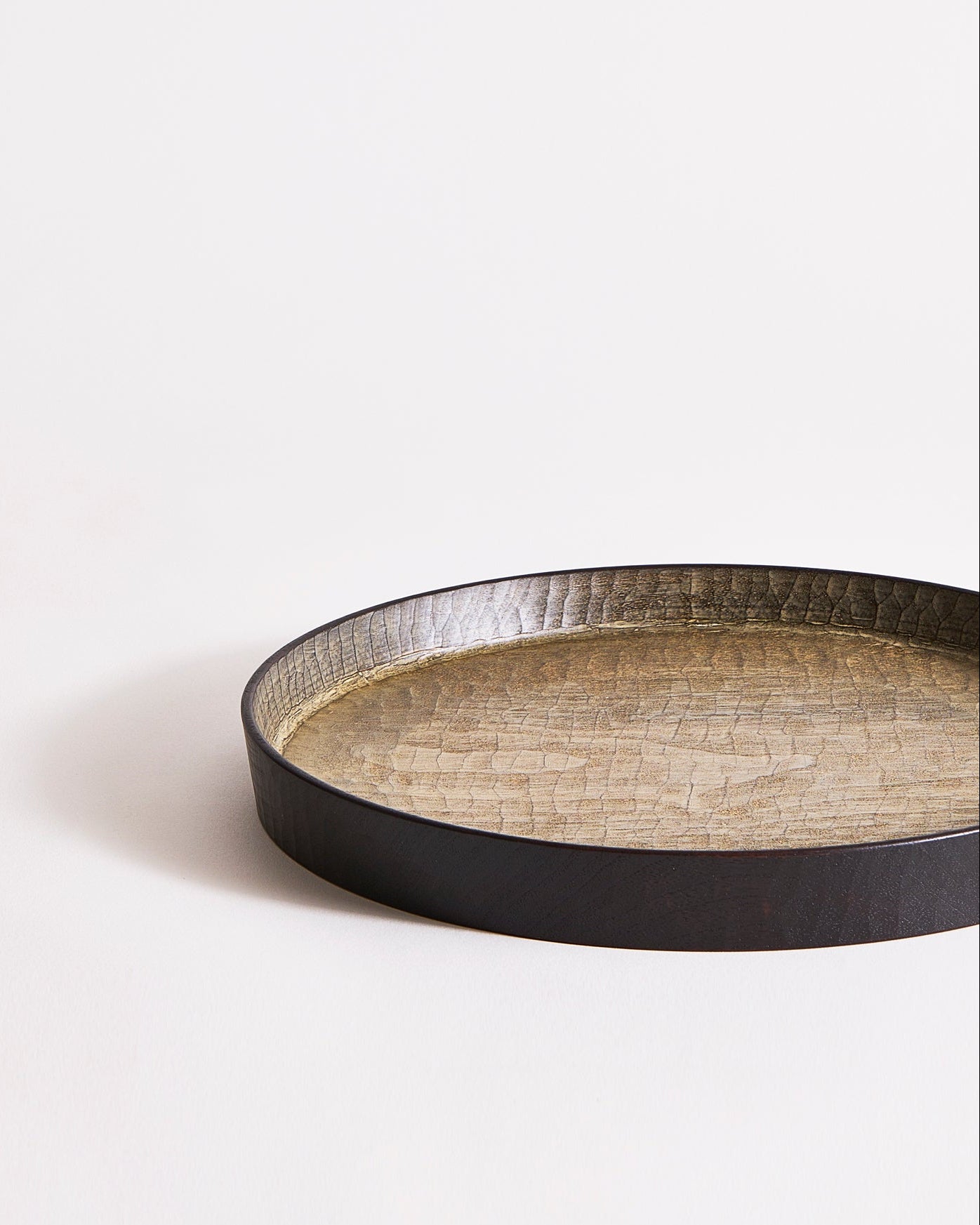 Wooden tray with black rim and beige interior by Ryuji Mitani on a light gray background