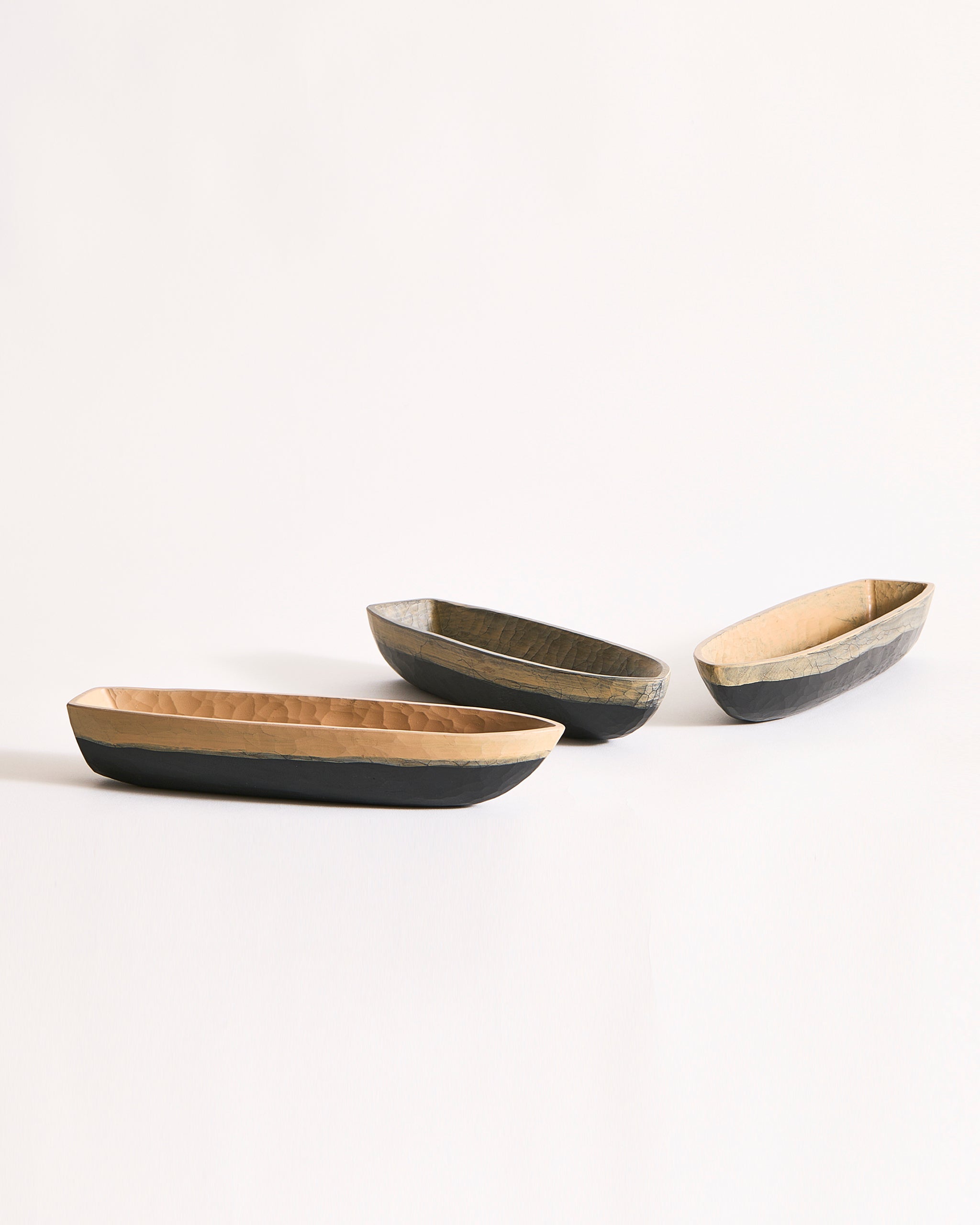 Three boat bowls with beige and black exteriors on a gray background