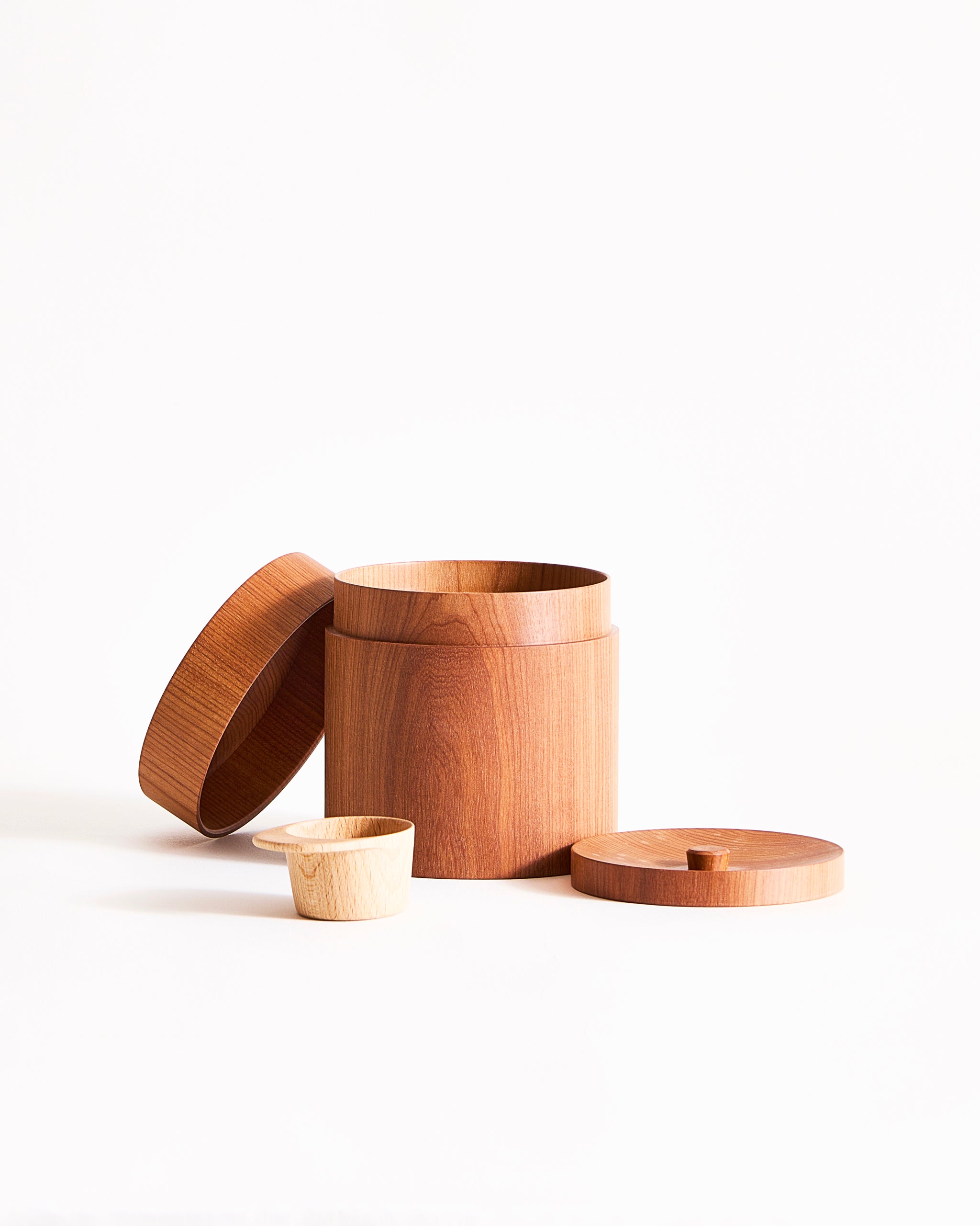 Wooden container with two lids and smaller wooden scoop on a graybackground