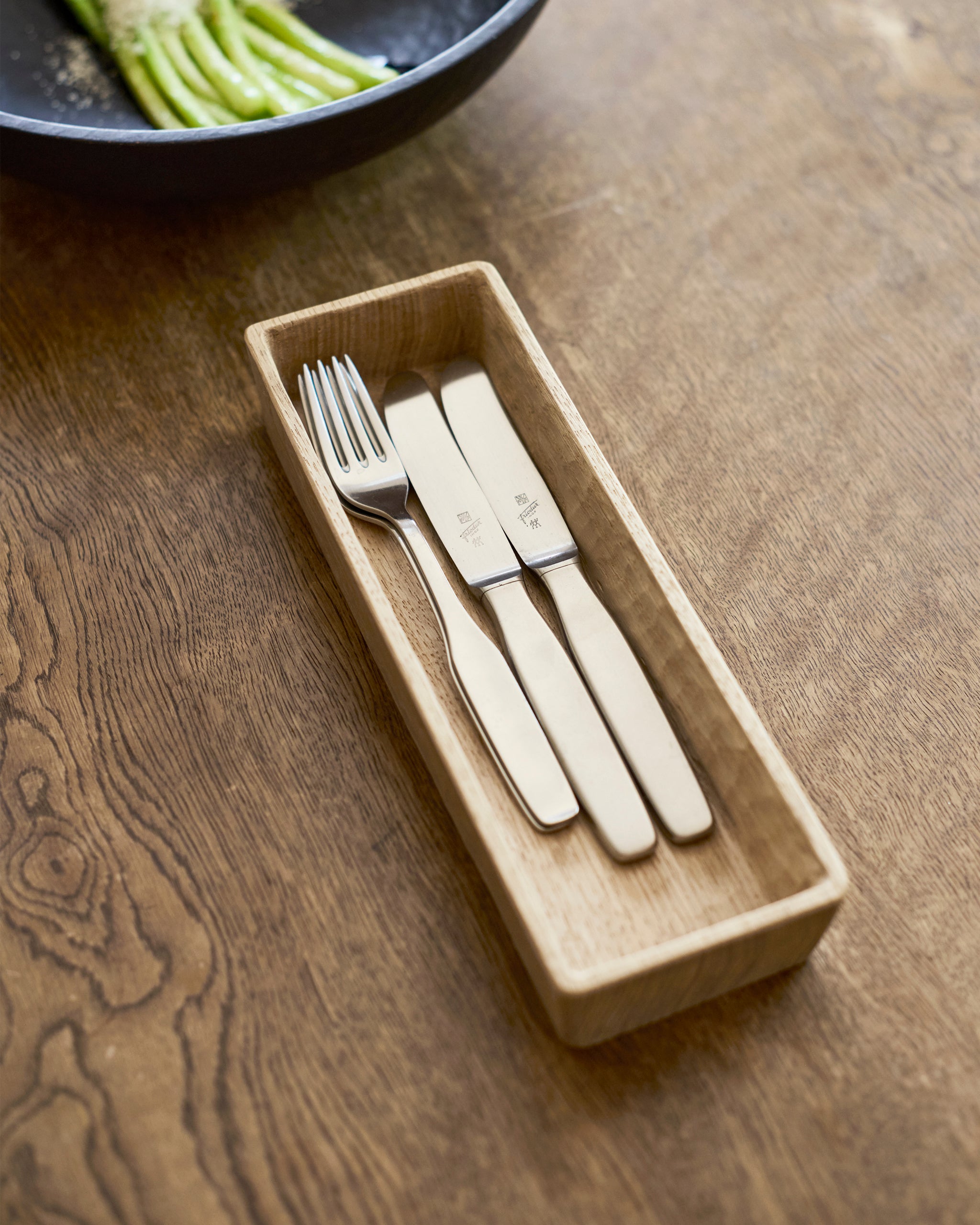 Set of cutlery in a wooden box by Ryuji Mitani  on a wooden surface