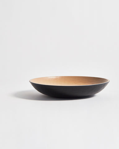 Side view of wooden bowl with beige interior and a black exterior by Ryuji Mitani on a light gray background
