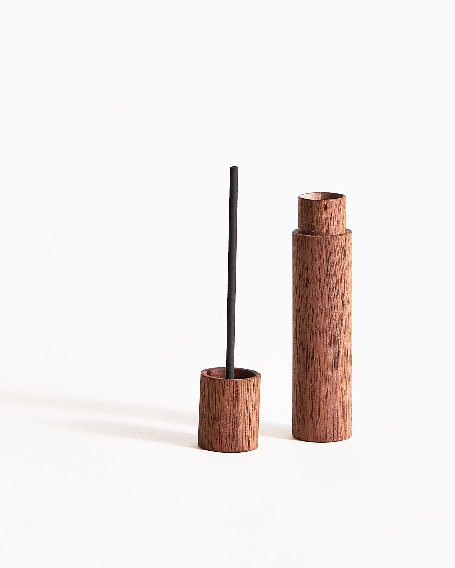 Lid and open wooden incense case with a charcoal incense on lid on a gray background