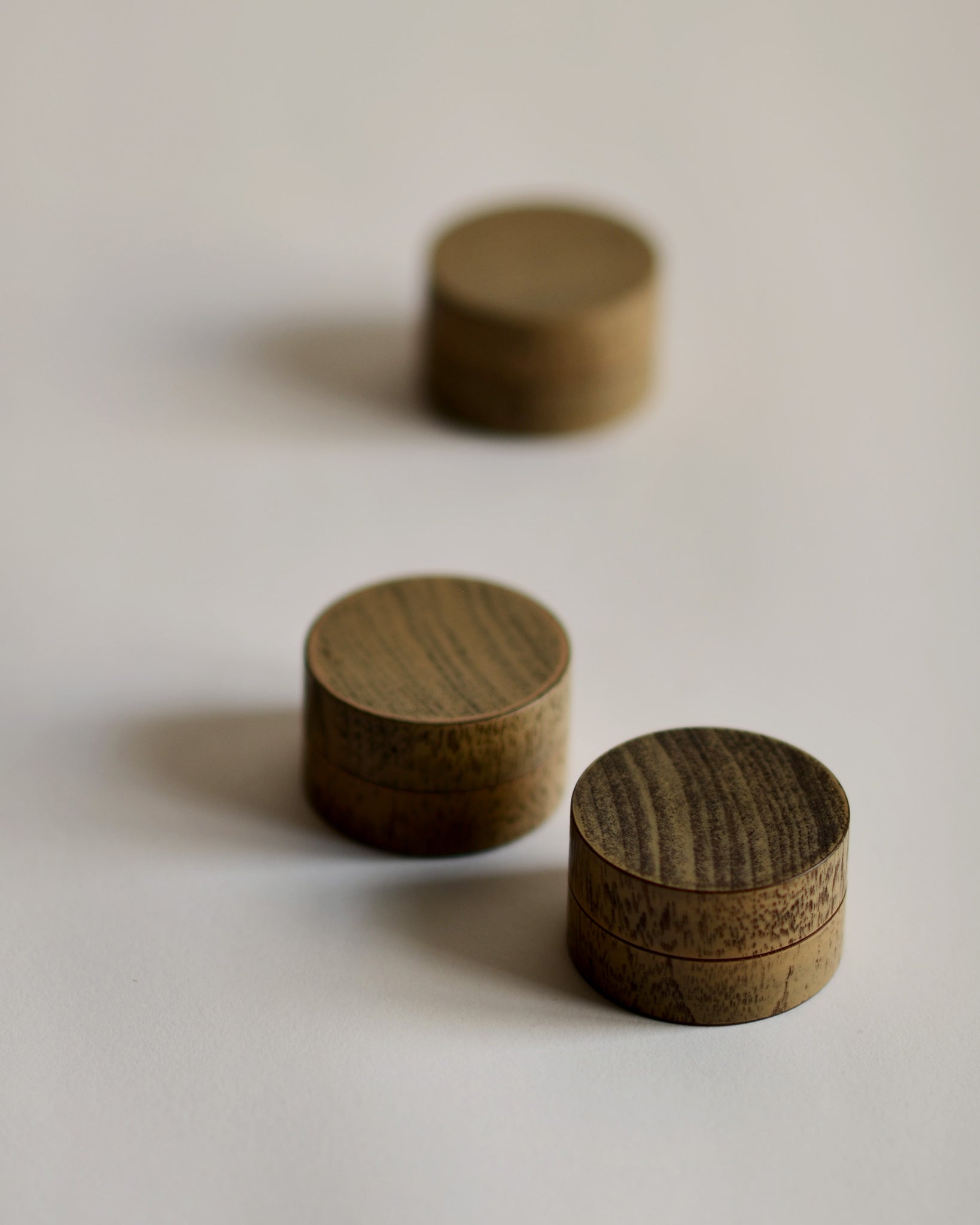 Side view of 3 Jewelry Boxes by Ryuji Mitani scattered against white-gray background.