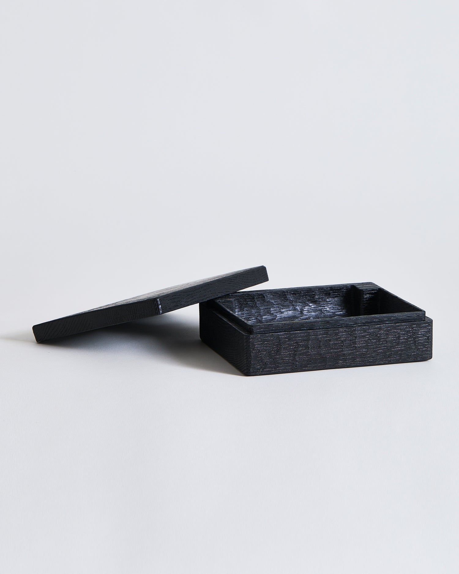 Black rectangular, wooden box with lid by Ryuji Mitani on a light gray background