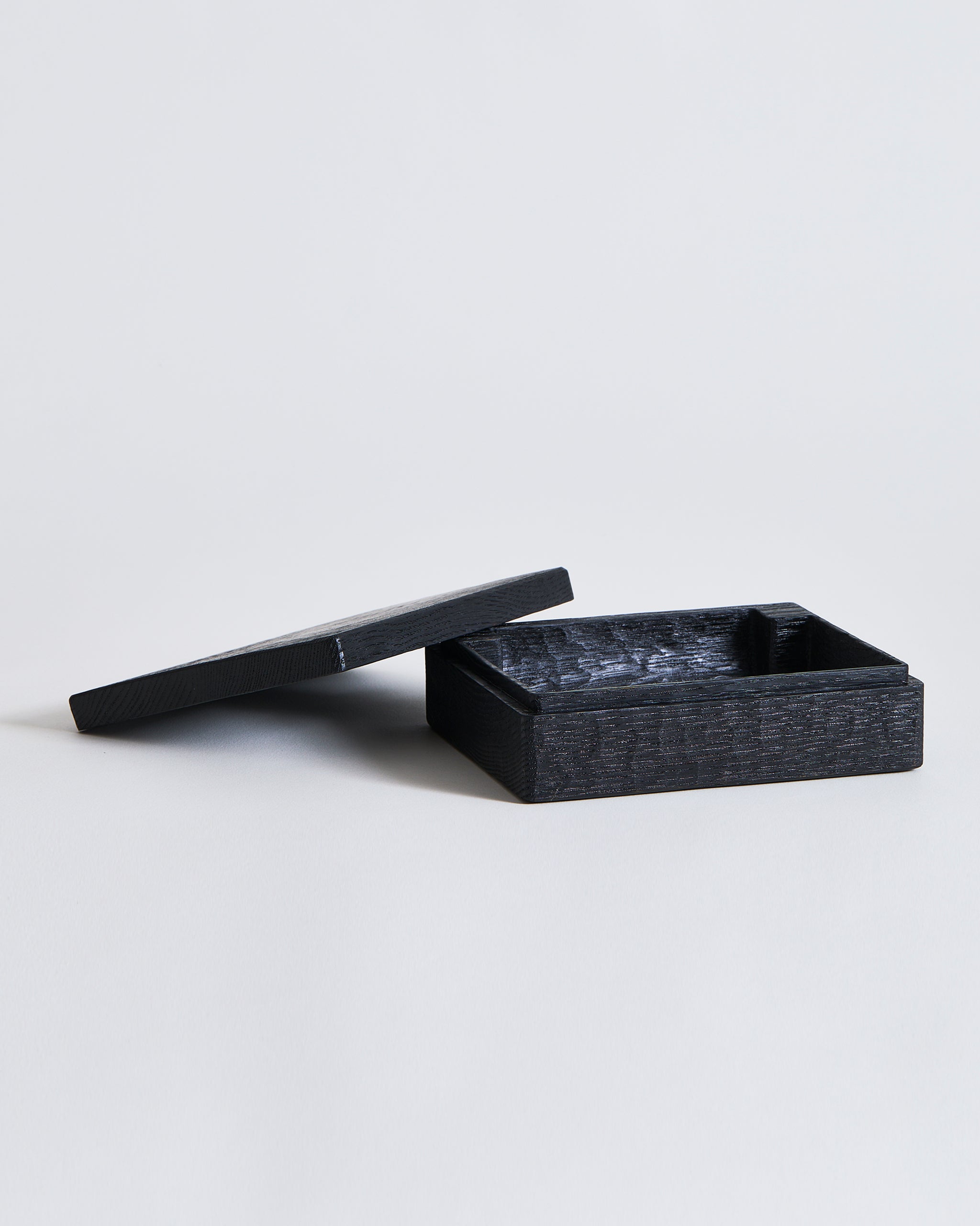 Black rectangular, wooden box with lid by Ryuji Mitani on a light gray background