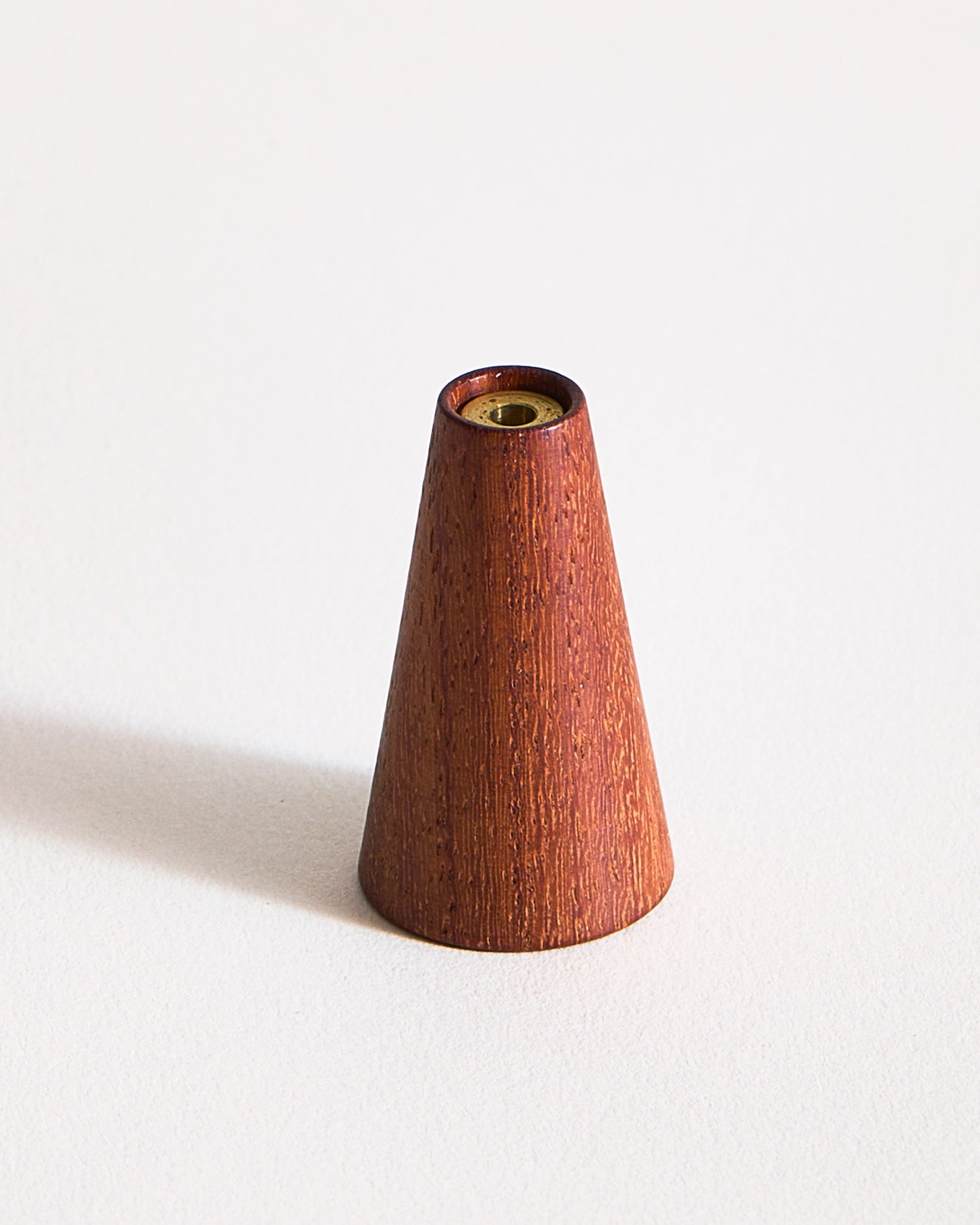 Warm, reddish brown wooden cone-shaped incense holder by Ryuji Mitani on a graybackground