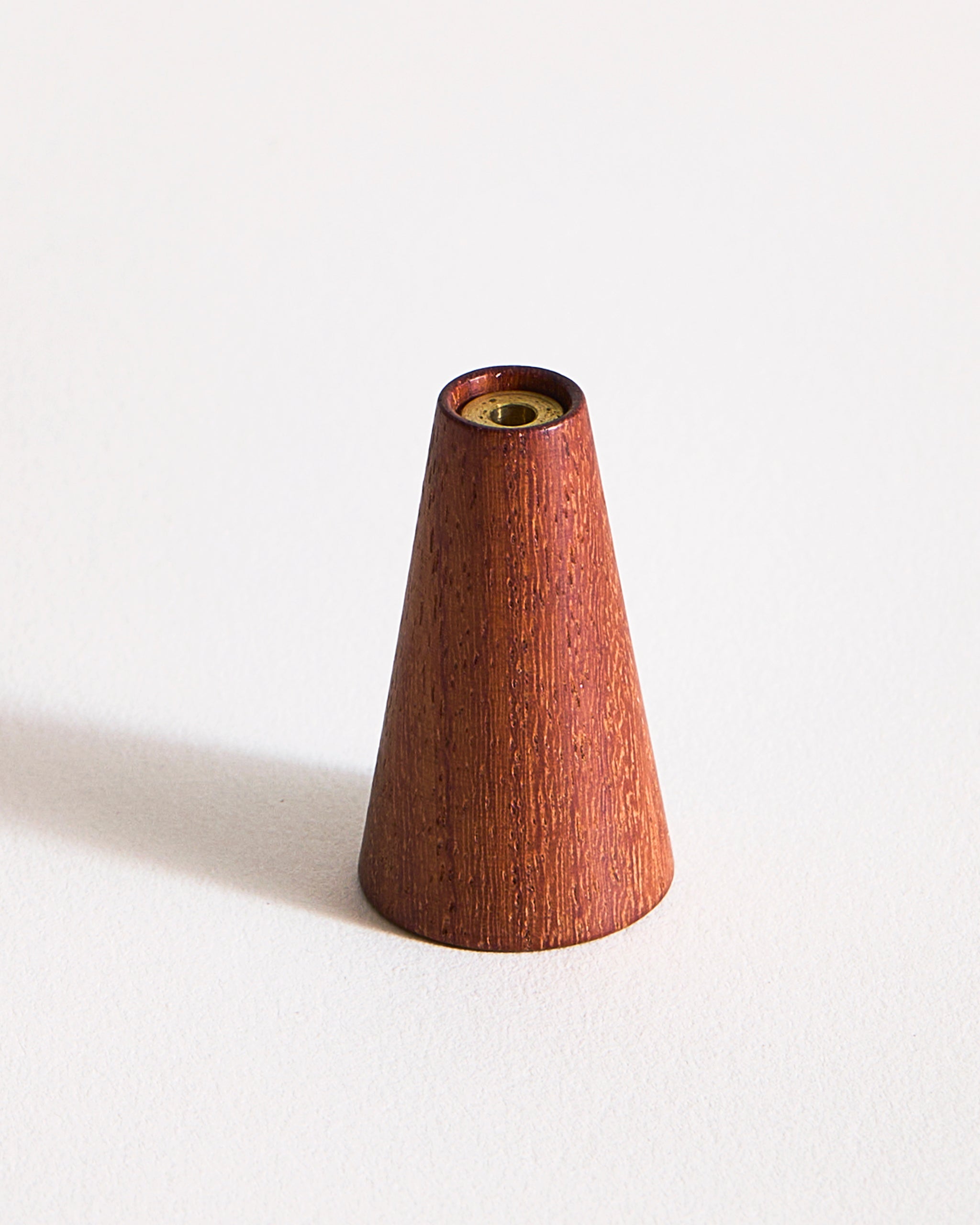 Warm, reddish brown wooden cone-shaped incense holder by Ryuji Mitani on a graybackground
