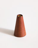 Warm, reddish brown wooden cone-shaped incense holder by Ryuji Mitani on a graybackground